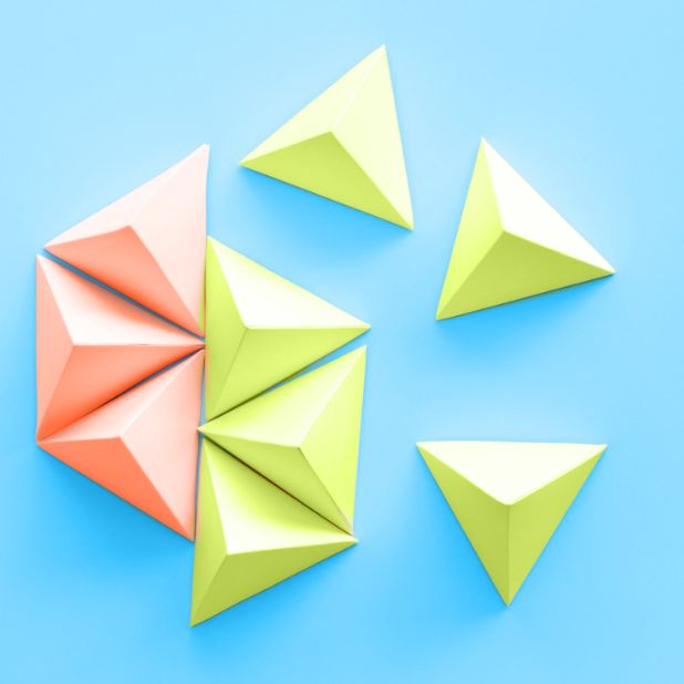 Paper origami triangles in various colors on a blue background, symbolizing creativity and leadership for a regenerative future.